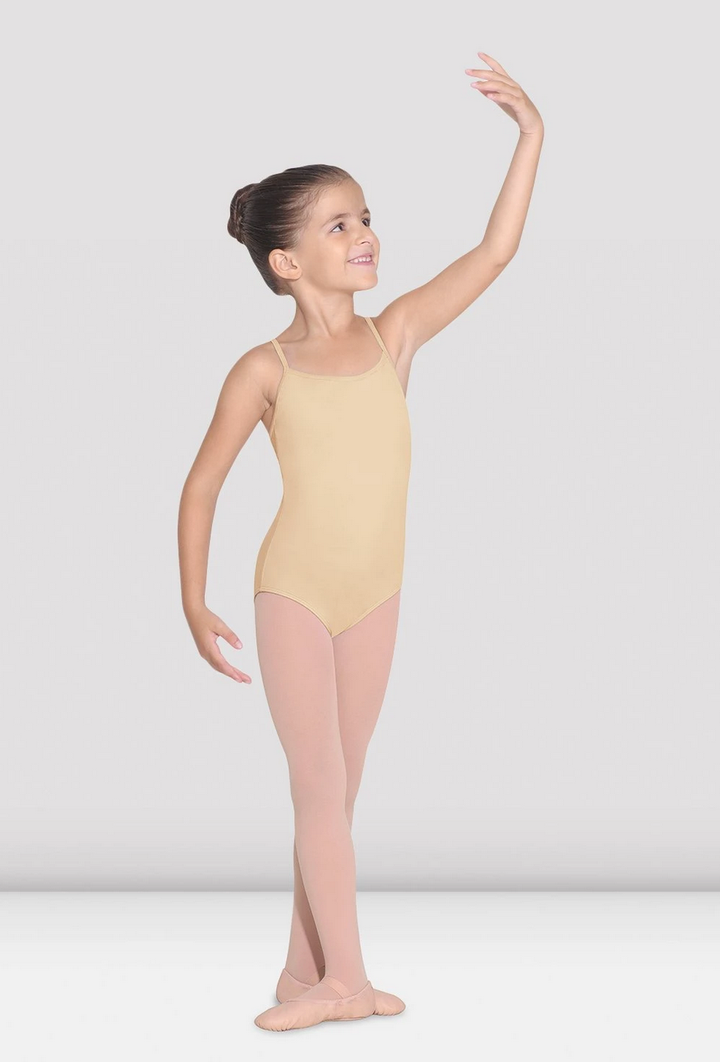 A young girl wearing a beige camisole leotard with a mid-high back and scoop front, posing with one arm raised gracefully.